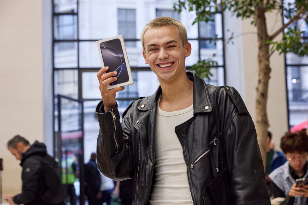 A person holding a new iPhone box and smiling